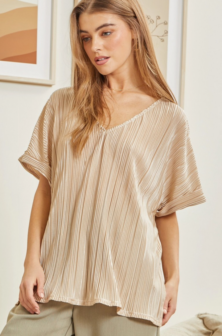 Woman wearing a beige pleated blouse in a casual setting